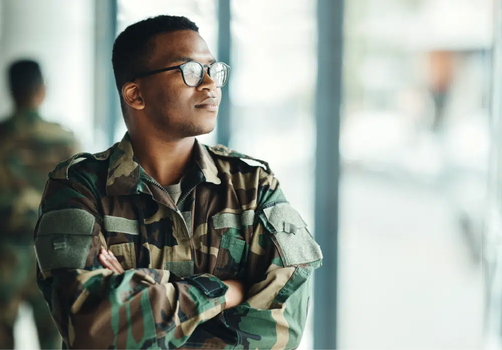 confident-soldier-thinking-by-window-with-arms-crossed