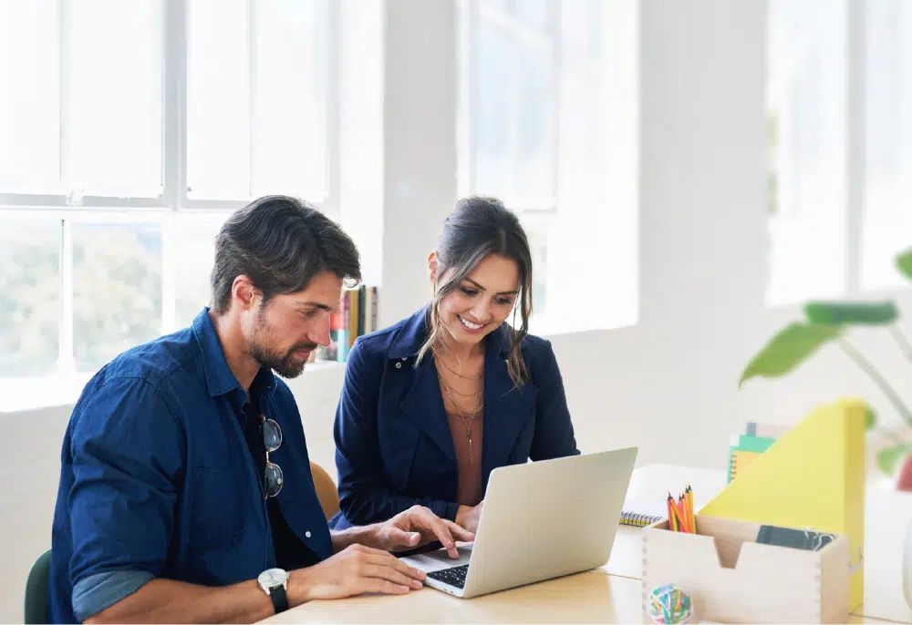 smiling coworkers working on laptop in the office